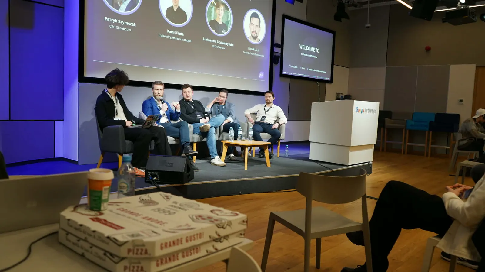 Panel discussion on stage with pizza boxes in the foreground
